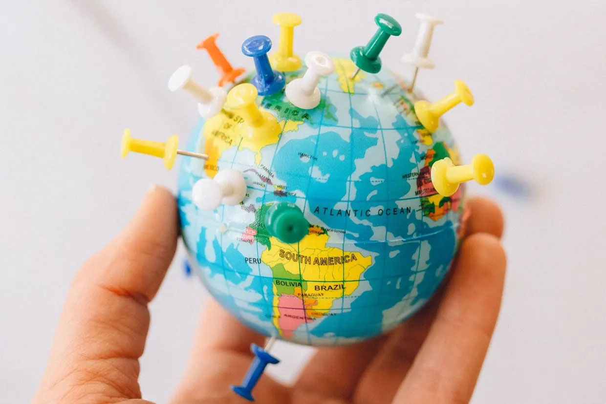 pins in world globe in hand