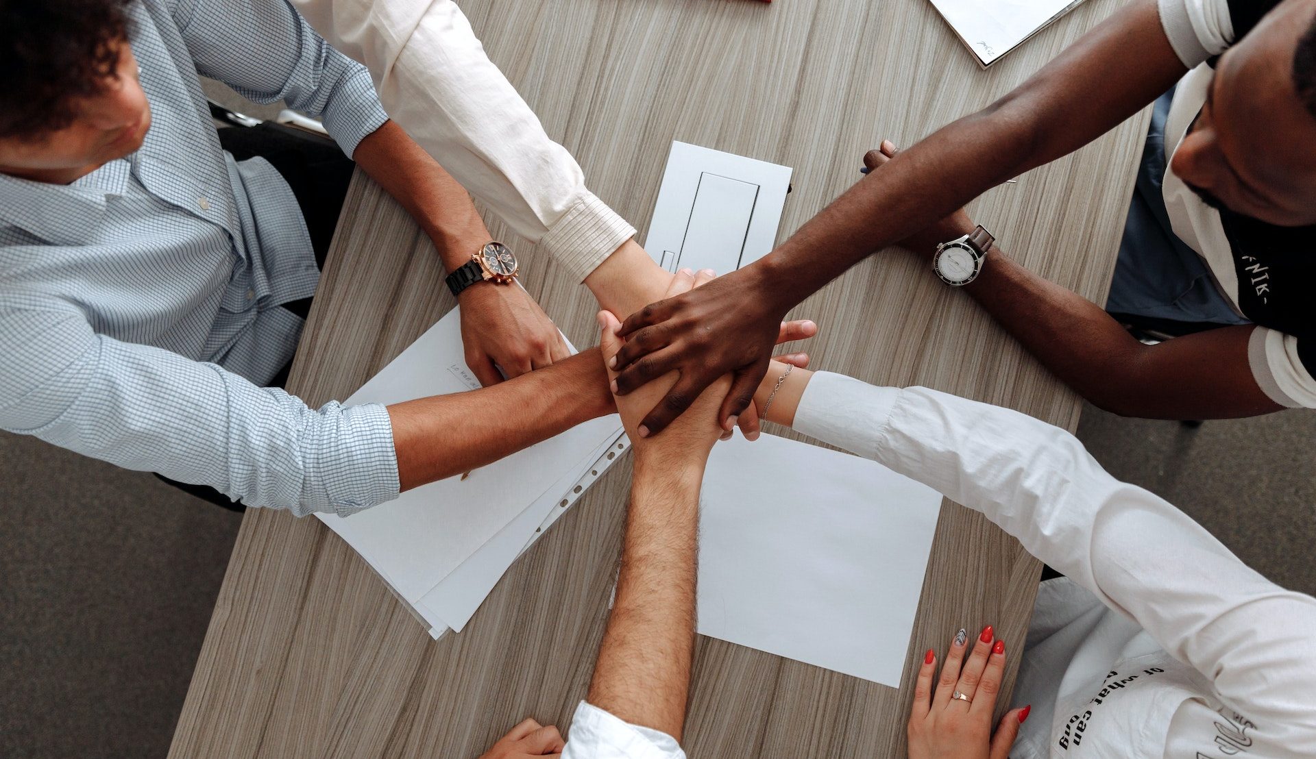 A group of multi-ethnic people working in an EOR putting their hands together